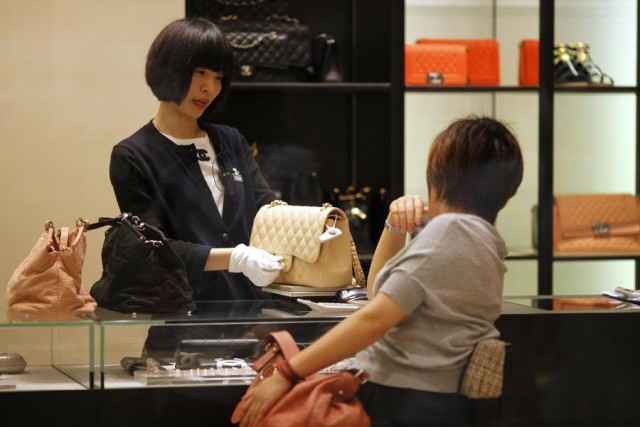 A woman shops for handbags at a Chanel luxury boutique at the IFC Mall in Shanghai in this June 4, 2012 file photograph. Wealthy Chinese are likely to buy fewer luxury goods again this year after the steepest cut-back on spending in three years. Overall spending by wealthy Chinese fell by 15 percent and gift-giving fell by a quarter in 2013, the third consecutive year of decline, according to a survey by the Hurun Report. REUTERS/Carlos Barria/Files (CHINA - Tags: BUSINESS)